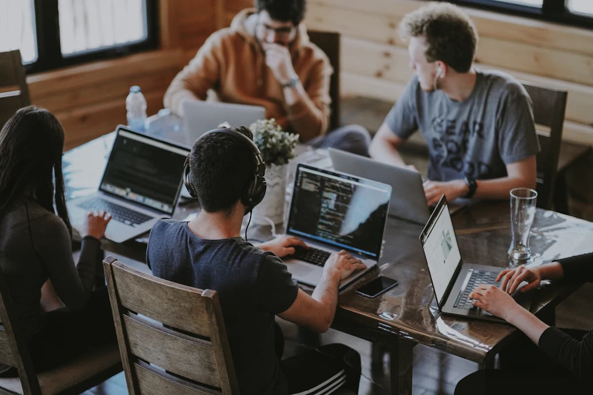 People working together around a table with laptops and code on their screens